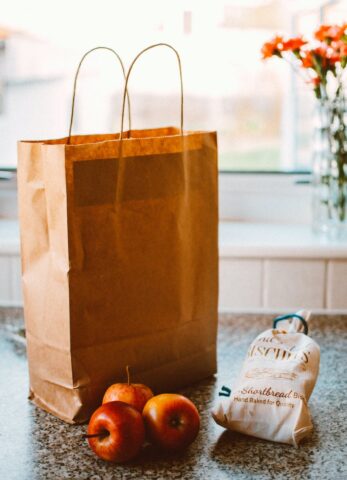 several apples beside bread pack and brown paper bag
